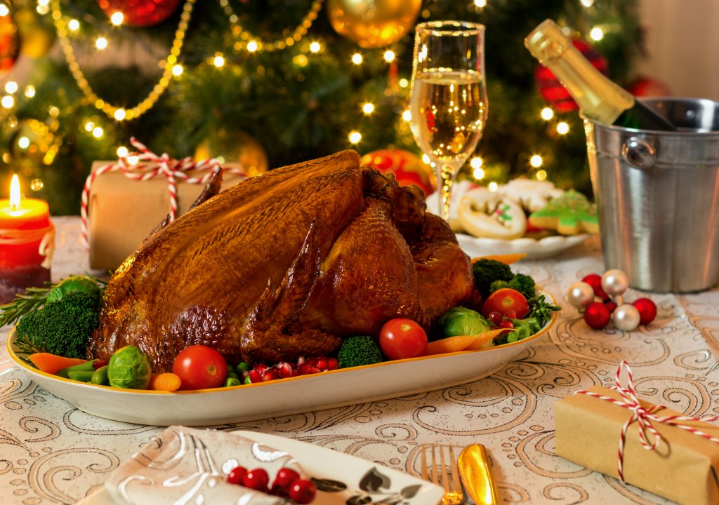 Roasted turkey on Christmas Dinner styles dining table in front of christmas tree