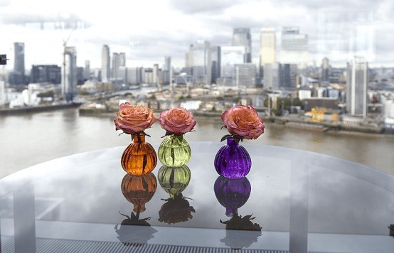 small coloured vases with pink roses in on balcony overlooking city