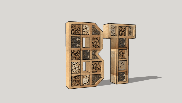 Pollinator habitat letters "bt" designed with varied fill patterns such as bamboo, logs, and drilled holes, standing upright on a flat surface.
