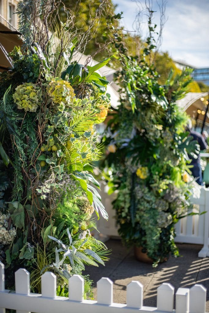 Green and yellow floral arrangement featuring roses and mixed foliage.