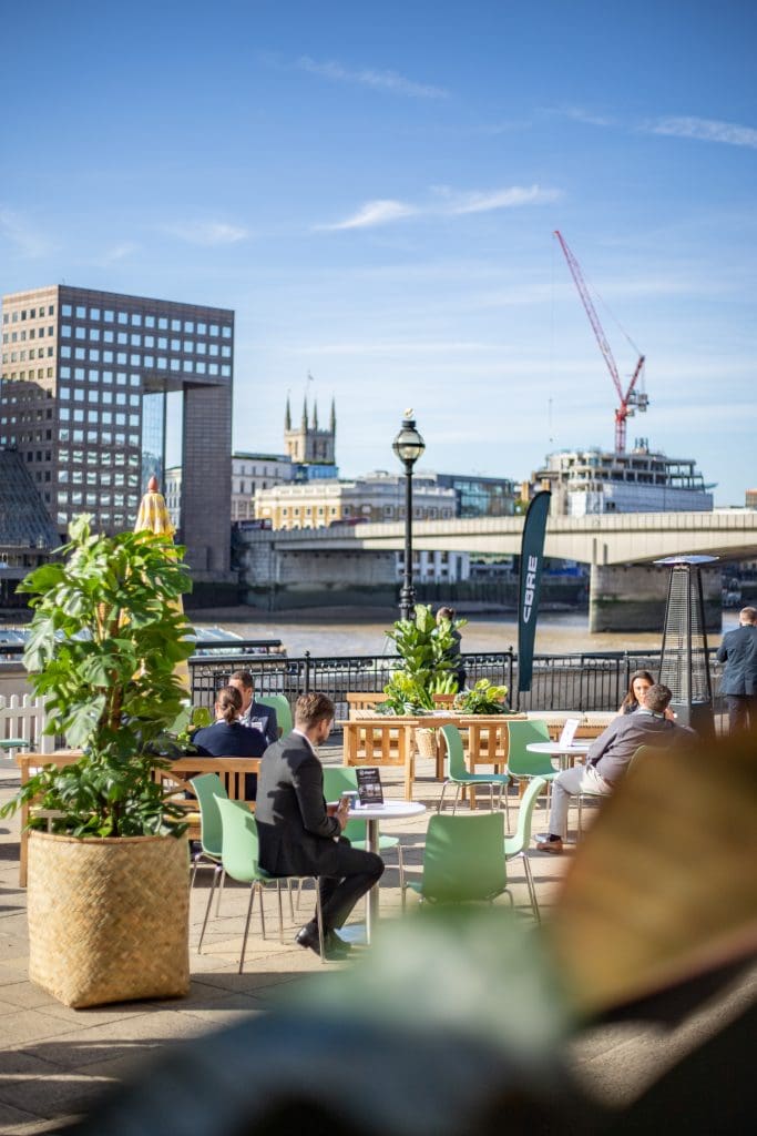 Thames riverside terrace with cbre planting installation and tower bridge in the background.